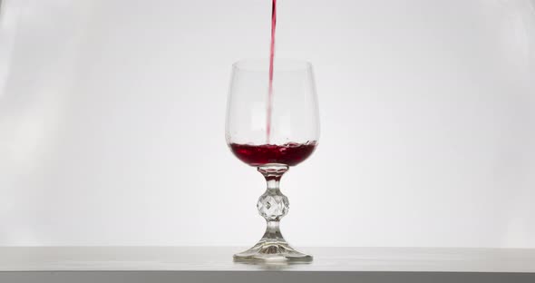 Close-up Shot, The Red Wine Is Pouring Into a Glass. White Background