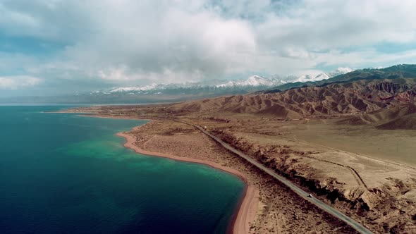 Aerial view of the lake shore with snowy mountains