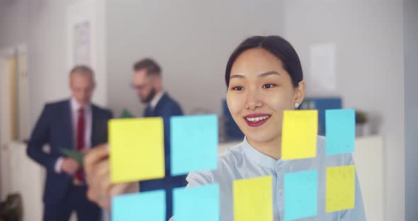 Asian Female Employee Write on Colorful Sticky Notes Develop Business Project in Office