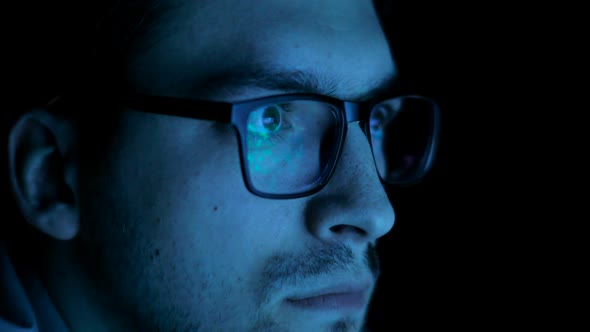 Reflection of the Screen in the Man's Glasses in the Dark
