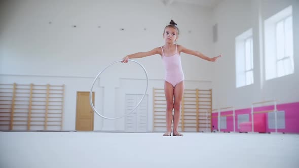 A Little Girl Training in the Sports Hall with a Hoop