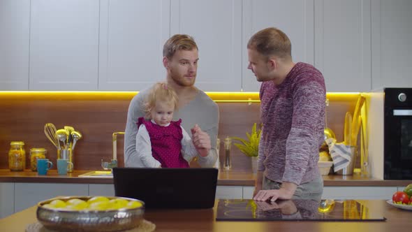 Same-sex Parents with Child Relaxing in Kitchen