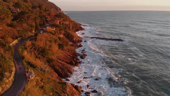 Aerial footage: waves hitting the rocks while camera moving forward at sunset