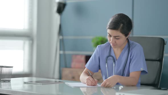 Indian Female Doctor Writing on Paper in Office