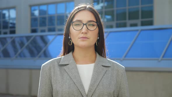 Young Woman in Suit and Glasses Smiling at Camera on the Street