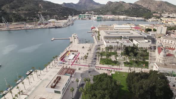 Cartagena touristic port and cityscape with El Zulo sculpture in background, Spain. Aerial circling