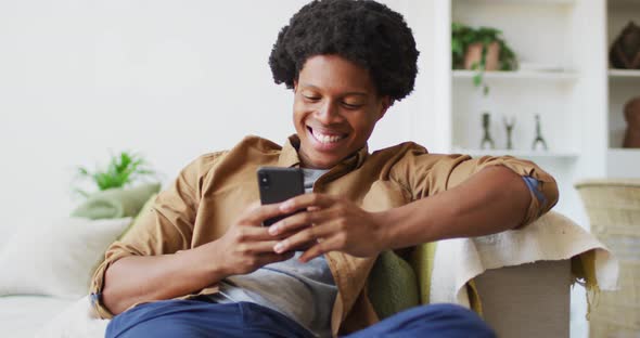 Happy african american man using smartphone at home