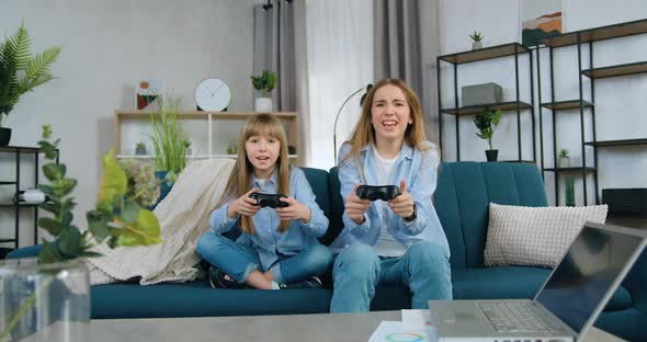 Two Sisters-Eldest and Younger Spending Joint Leisure at Playing Video Games