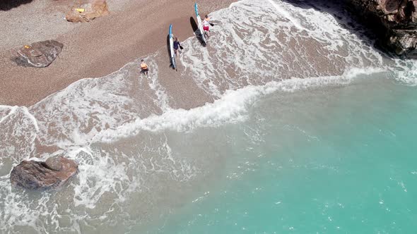 Man and Woman Go Out of Sea Carrying Paddle Boards