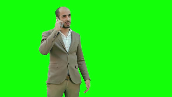 Young Man Talking on the Phone and Actively Gesturing on a Green Screen, Chroma Key.
