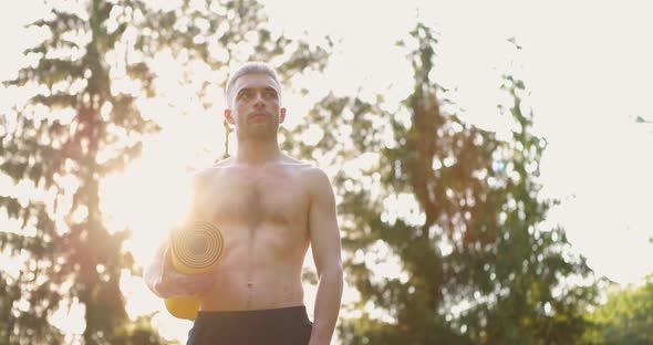 Young Man with Sport Mat in Hands Standing and Looking Forward