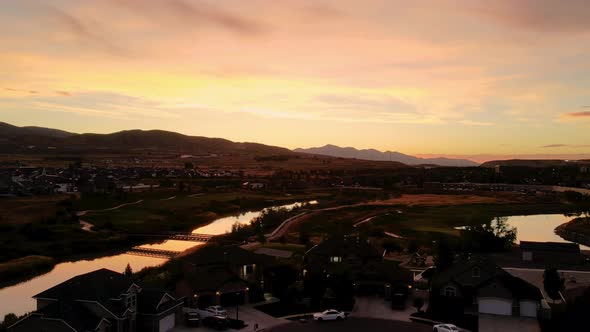 Aerial hyperlapse with a colorful sunset reflecting off the surface of a river and lake in a suburba