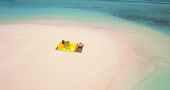 Aerial drone view of a man and woman couple having a picnic meal on a tropical island beach