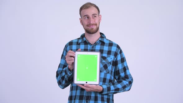 Happy Bearded Hipster Man Thinking While Showing Digital Tablet