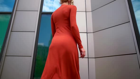 the Blonde in the Red Dress Goes To the Wall and Turns. the Camera Moves From Bottom To Top