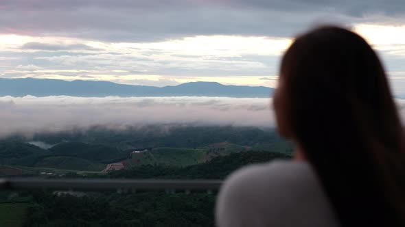 Blurred rear view of a female traveler looking at a beautiful mountain views on foggy day