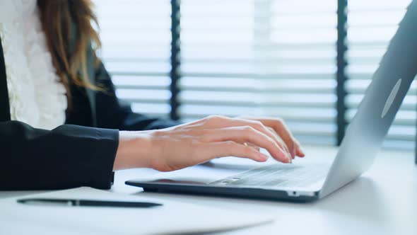 Close up hands of business woman typing on laptop keyboard on desk.