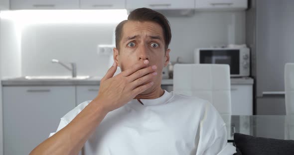 Closeup Portrait of Scared Man Bulging Eyes and Covering Mouth in Fright Reacting on Horrible