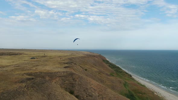 Extreme Sports, a Man Is Paragliding Over the Hills Near the Sea, Aerial Shot