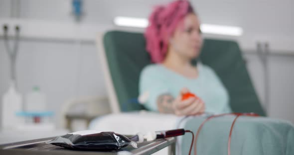 Young Woman in Headphones Listening to Music Lying on Couch and Donating Blood