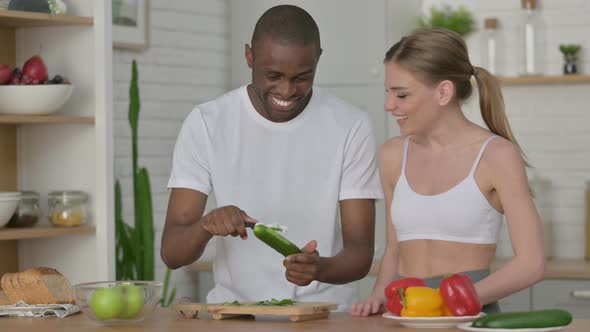 Athletic Couple Peeling Cucumber in Kitchen