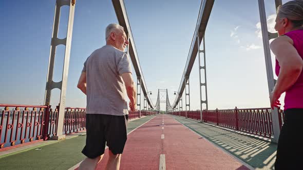 Active Pensioners Enjoy Jogging on Pedestrian River Bridge