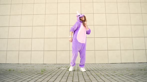 Funny cheerful happy young woman dancing outdoors on yellow wall