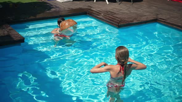 Children Playing with Ball in Swimming Pool in Slow Motion