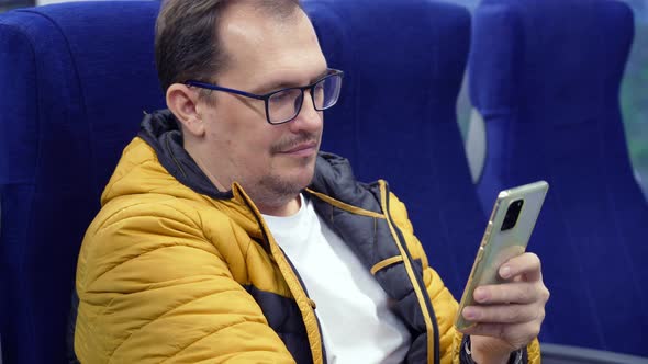 Guy in Eyeglasses Looking Social Media Texting Messages Using Cell Phone While Riding Home By Train