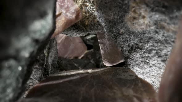 Camera Pans Inside a Pile of Gray and Brown Granite Stones Against a Black Background