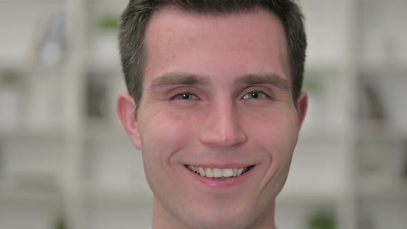 Close Up of Face of Cheerful Young Man Smiling at the Camera 