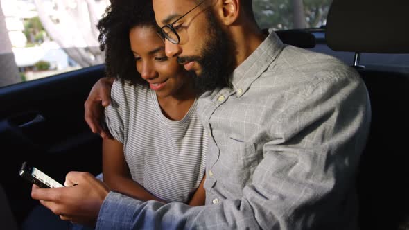 Couple using mobile phone while travelling in car