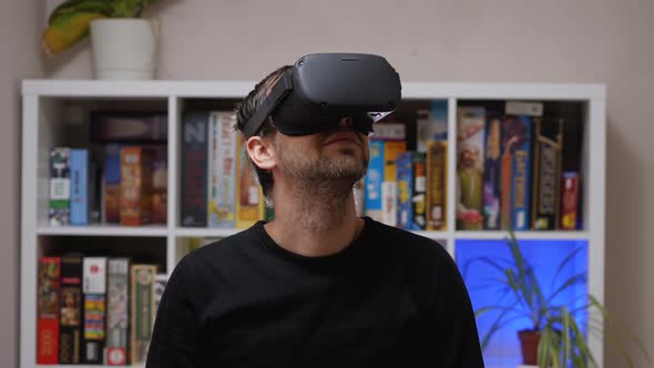 Close-up of a Caucasian man in a black sweatshirt wearing VR glasses on his head and smiling