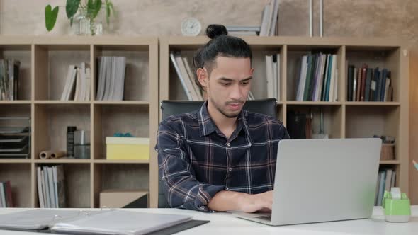 Male worker works with laptop in casual creative office.