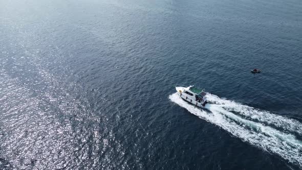 White big boat motion on blue water aerial view. Flight over a white yacht in motion.