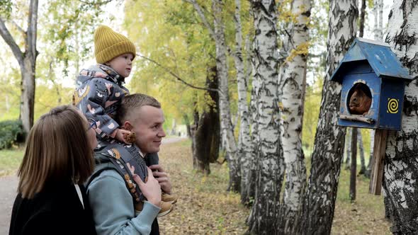 A Young Family Walks in the Park and Watches As a Squirrel Gnaws Nuts