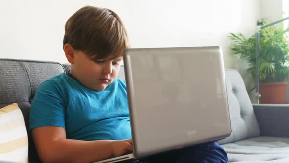 Boy using laptop in living room 4k