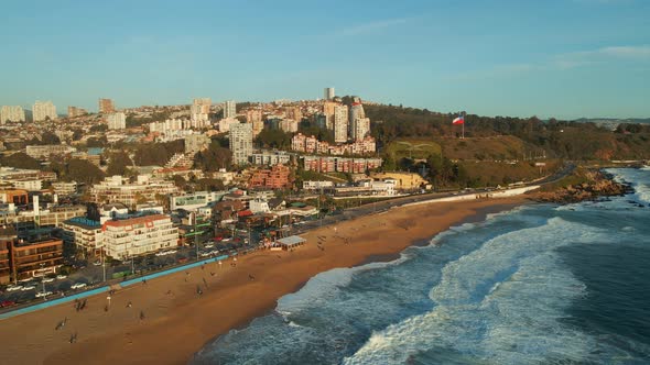 Aerial view dolly right flying above Reñaca golden Chile scenic sandy beach waterfront ocean waves