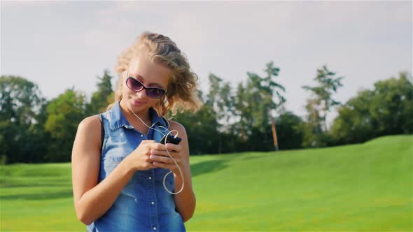 A Young Attractive Woman Walks in a Wellgroomed Park on a Summer Day