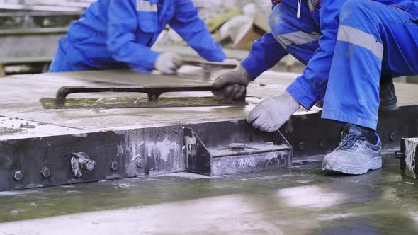 Workers leveling ferroconcrete items manually