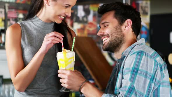 Happy couple interacting while having milkshake