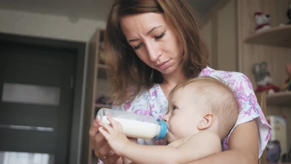 Beautiful Mom Feeds Infant Son From Milk Bottle
