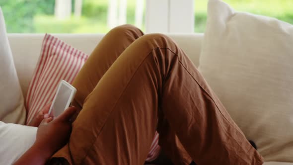 Man lying on sofa and digital tablet in living room