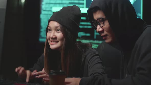 Young Asian Couple Hacker Using Computer Hacking And Celebrating, Code On Multiple Computer Screens