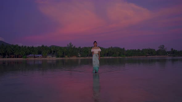 Young Asian Woman Walking Alone in the Sea at Beautiful Sunset Thailand