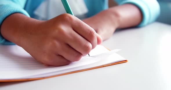 Mid-section of school kid doing homework in classroom at school