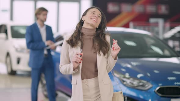 Joyful Young Beautiful Woman Dancing in Slow Motion in Car Dealership