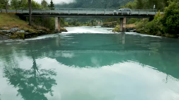 Drone flying under a bridge in Loen, western Norway. Beautiful turquoise water flowing.