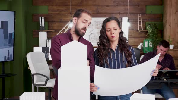 Team of Architects Holding Blueprints with Building Models in the Office