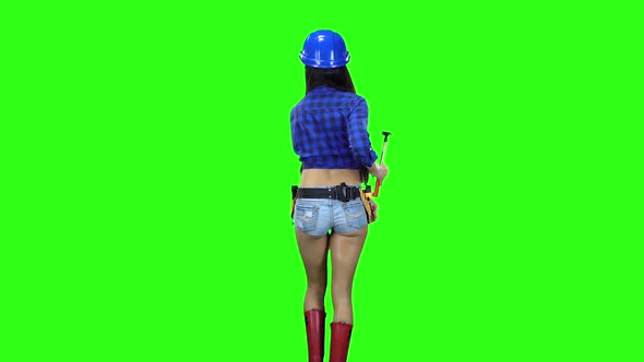 Rear View of Girl in Hat and Shorts with a Hammer on the Belt Going on Green Background